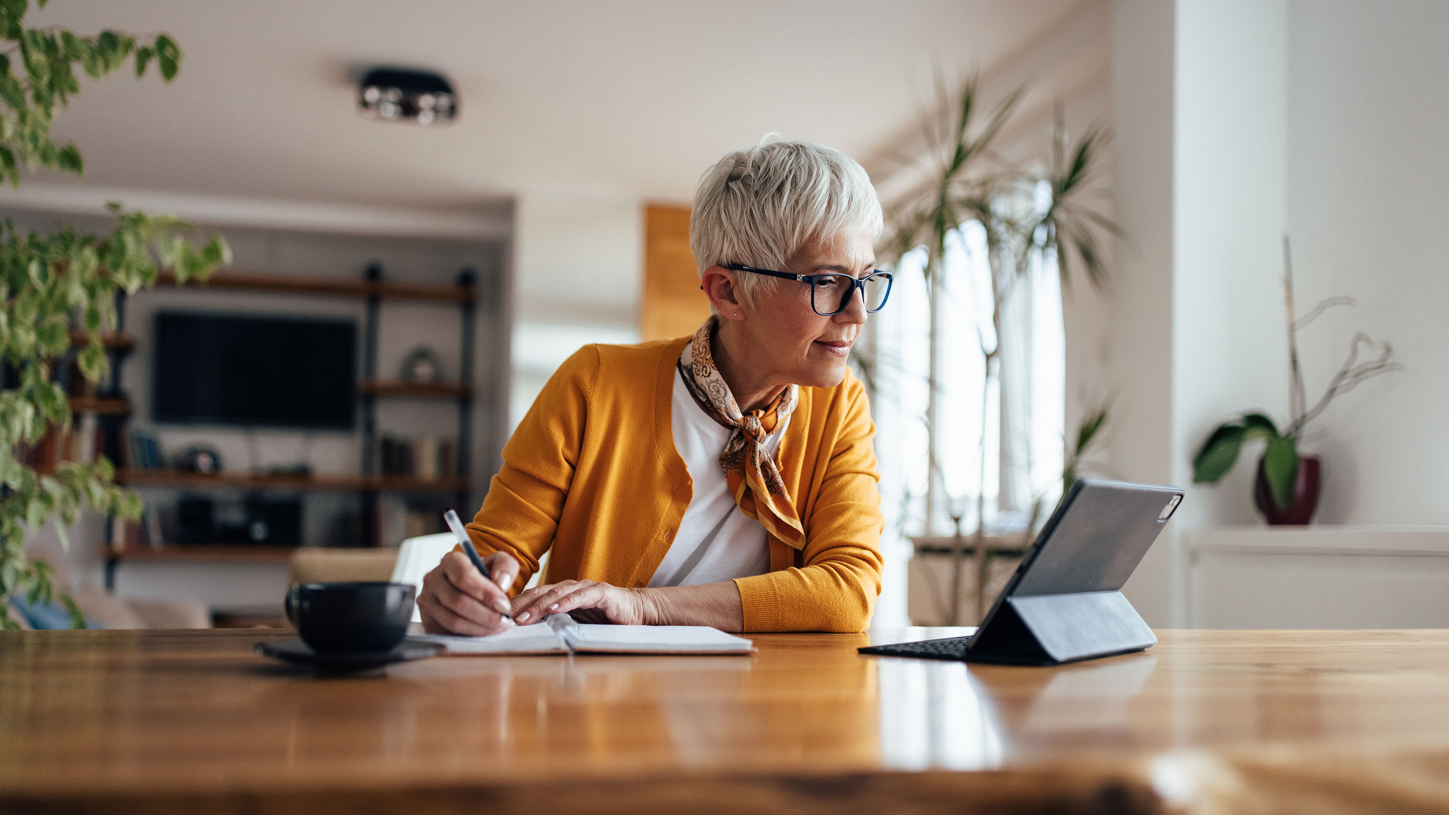 Person at home using an iPad and taking notes